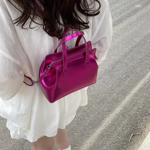 Metallic magenta faux leather handbag with adjustable strap shown from a side-view on model