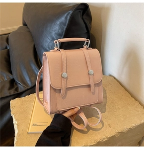 Detail of pink faux leather backpack featuring vertical embossed texture and metal buckle