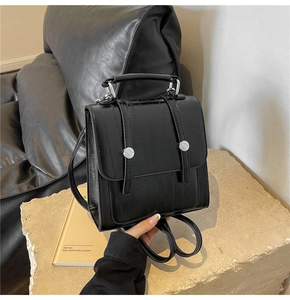 Close-up of black textured leather backpack featuring vertical grain and silver metal clasp
