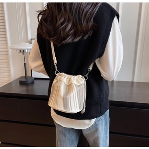 Detail einer weißen Beuteltasche mit langen silbernen Fransen und genarbtem Leder