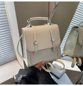 Detailed close-up of cream crocodile pattern backpack with elegant metal buckle and straps