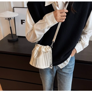 Detail der cremefarbenen Kordelzug-Beuteltasche mit silbernen Fransen an einem Modell