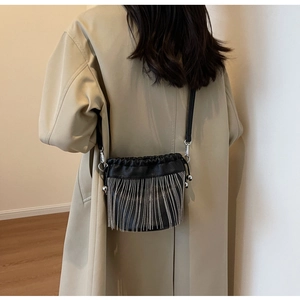 Detail der schwarzen Eimer-Tasche aus Kieselleder mit eleganten silbernen Fransenketten
