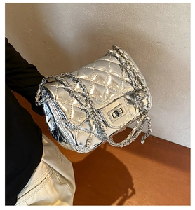 Detailed close-up of quilted silver leather bag with metallic chain and rotary lock