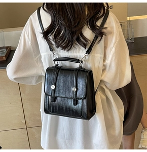 Detail of stylish black crocodile pattern backpack with silver buckles and flap closure