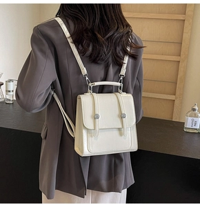 Detail of cream-white structured backpack on model with adjustable straps and silver buckle