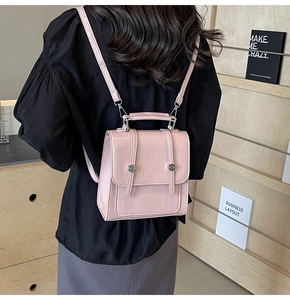 Detail of pink faux leather mini backpack with textured finish and silver studs shown on model