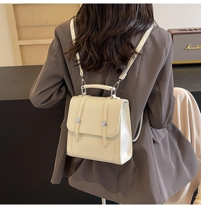 Detail of a creamy white PU leather mini backpack with vertical straps and metal buckle