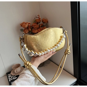 Détail du sac croissant doré avec perles blanches et grosse chaîne en métal argenté