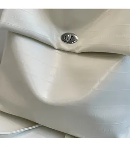 Close-up of white embossed leather texture and silver turn-lock hardware on a handbag