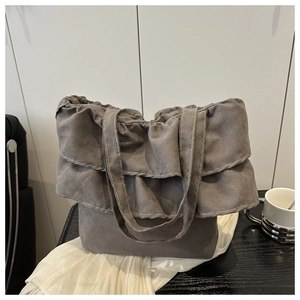 Detail of grey ruffled tote bag with multi-layer pleated design and suede texture