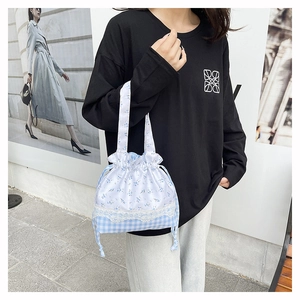 Detail of blue floral and checkered drawstring bucket bag with delicate lace trim