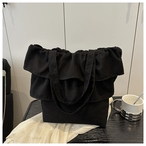 Detail of elegant black ruffled tote bag with layered design on wooden surface