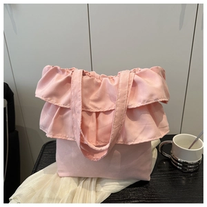 Pink ballet-style tote bag featuring layered ruffled pleats on a wooden table surface