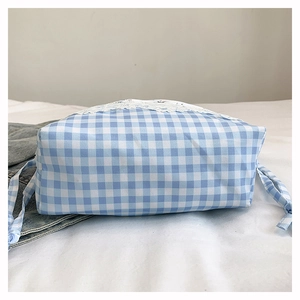 Detail of blue gingham lunch bag featuring white lace trim and drawstring closure