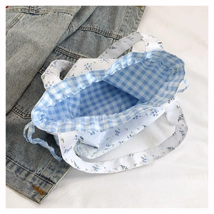 Macro view of blue floral drawstring lunch bag showing gingham lining and inner capacity