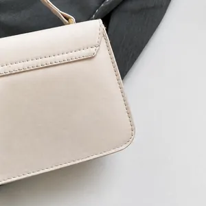 Detailed close-up of precise stitching on premium beige leather crossbody bag flap