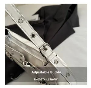 Detail view of adjustable white leather shoulder strap with silver metal grommets and buckles