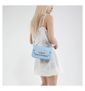 Close-up of light blue flap handbag featuring a rectangular gold metal twist lock buckle