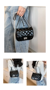 Detail of black quilted leather shoulder bag with silver chain strap and metal lock