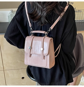 Detail of pink croc-embossed mini backpack showing glossy PU texture and buckle closure