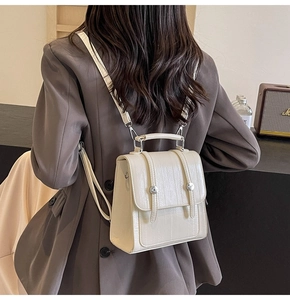 Detail of a beige textured faux leather backpack with metallic magnetic closure on a model