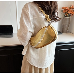 Détail du sac bandoulière en PU doré avec chaîne perlée et bandoulière nouée sur modèle