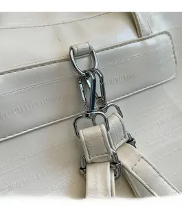 Close-up of polished silver hardware and ivory embossed leather straps on a backpack
