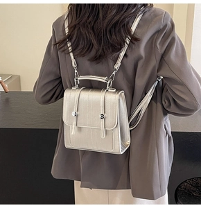 Detail view of a silver metallic textured mini backpack worn on model's back