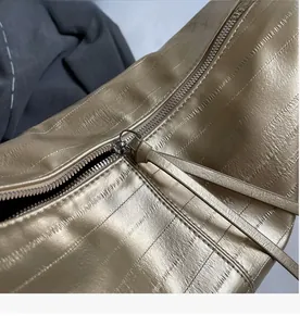 Detail shot of smooth silver metal zipper and soft leather pulls on tote bag