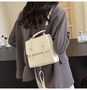 Detail of a beige faux leather mini backpack featuring vertical straps and metal buckles