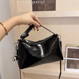 Glossy black textured bucket bag with silver bell charm and metal top handle strap
