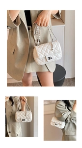 Close-up detail of white quilted crossbody bag with silver clasp and metal chain strap
