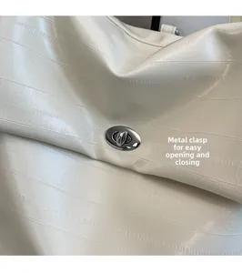 Detail of silver oval twist lock on cream textured leather backpack with secure closure