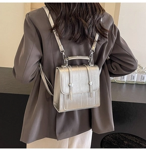 Detail of silver metallic textured mini backpack worn over a dark grey blazer