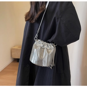 Modische silberne Fransen-Eimertasche mit Ketten zu einem schwarzen Mantel-Outfit