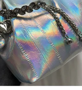 Detail of holographic bucket bag with silver chain and leaf pendant ornaments