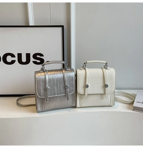 Detail of minimalist square crossbody bags in silver and cream with vertical textures