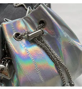 Detailed macro of silver laser drawstring bucket bag with shiny metal chain and hardware