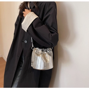 Detail der silbernen Metallic-Fransenbeuteltasche kombiniert mit einem schwarzen Damenmantel