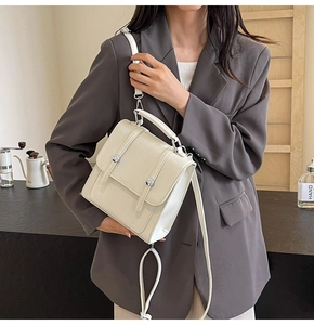 Detail of off-white leather crossbody bag with silver buckles in a cafe setting