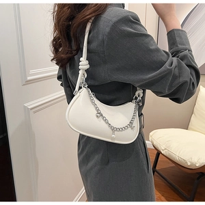 Détail du sac hobo blanc avec bandoulière nouée et chaîne argentée à breloques perles