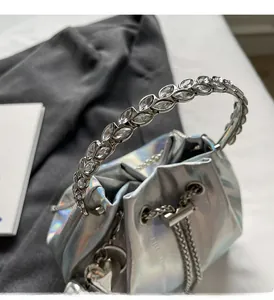 Detail view of silver holographic bucket bag with crystal-encrusted handle and chain strap