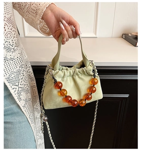 Detail of light green drawstring bucket bag with amber resin beads and silver chain