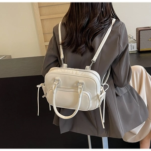 Detail of a creamy white PU leather backpack with silver zippers on a grey suit model
