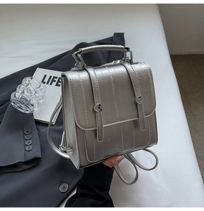 Detail of silver textured leather backpack featuring metallic finish and metal handles