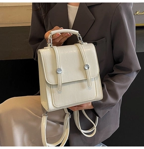 Detail of cream white faux crocodile backpack showing textured leather and silver clasp