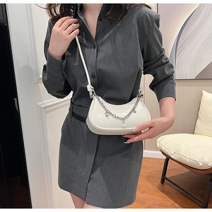 Détail d'un sac demi-lune blanc avec des chaînes argentées et des perles décoratives