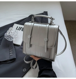 Detail of silver metallic textured backpack with top handle and round hardware buckles