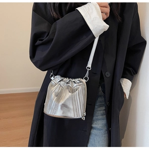 Detail einer silbernen Beuteltasche mit vertikalen Metallketten und Kordelzug am Modell